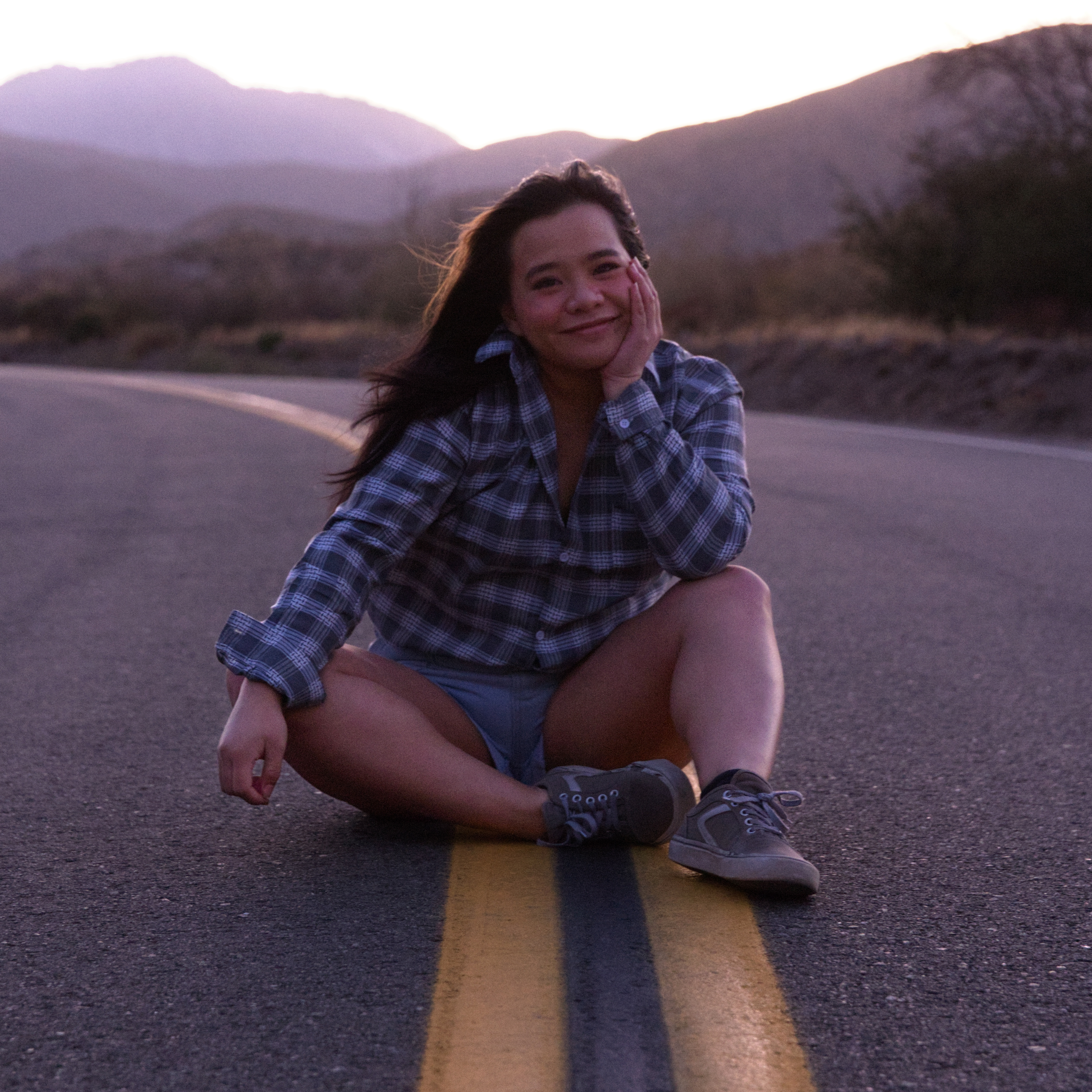 girl sitting in the middle of a road in the middle of nowhere, content